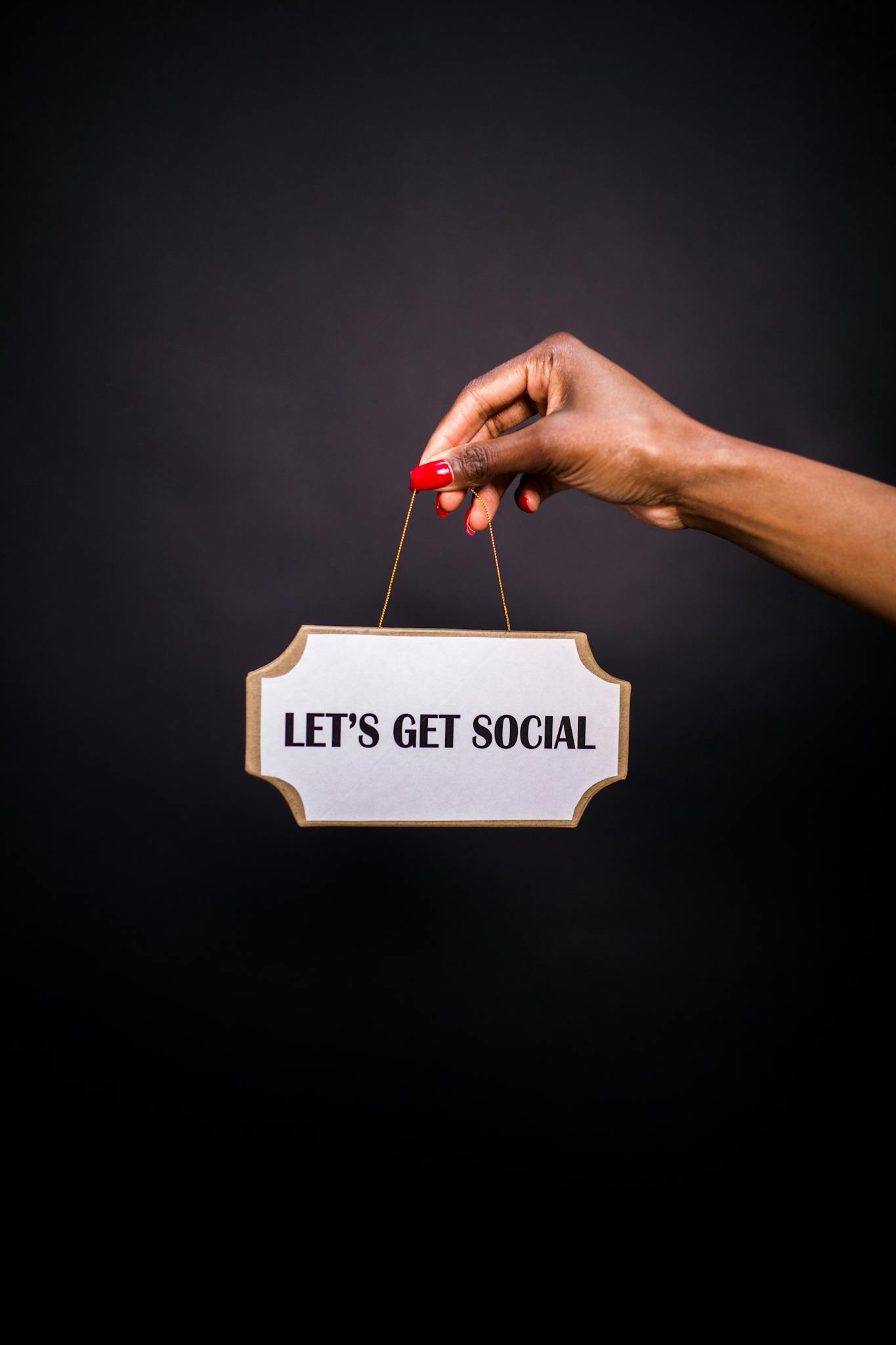 Servizi 4 Close-up of a hand holding a sign with 'Let's Get Social' on a dark background.