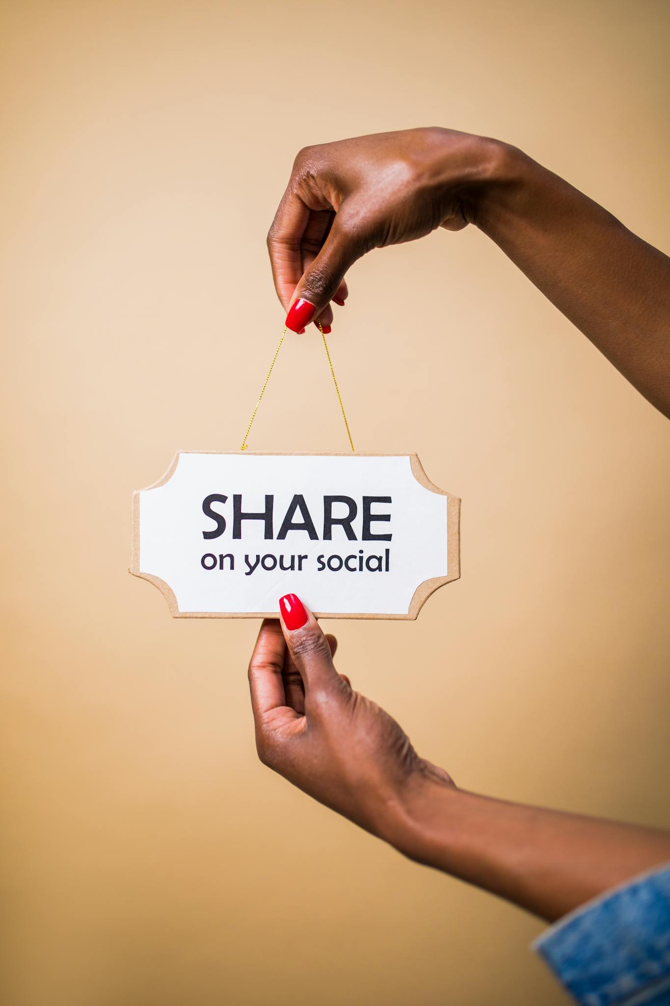Servizi 5 Close-up of a person's hand holding a 'Share on your social' sign against a beige background.